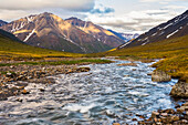 A clear stream flows over the tundra beneath the mountains of the Brooks Range; Alaska, United States of America