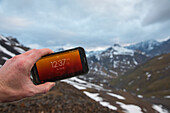 A man displays the time on his phone after midnight on June 24 in the Brooks Range when the sun never sets; Alaska, United States of America