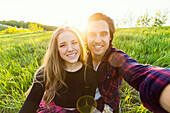 Junges Paar in einem Park, das für ein Selbstporträt mit seinem Handy posiert; Edmonton, Alberta, Kanada