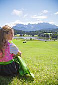 A girl in typical dress looks at the Geroldsee, Gerold, Garmisch Partenkirchen, Bayern, Germany
