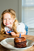 Happy Caucasian girl near birthday cupcake