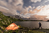 Hiker and tent on the shore of Lacs De Cheserys at night with Mont Blanc massif in background, Chamonix, Haute Savoie, France, French Alps, Europe