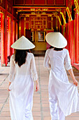 Two Vietnamese women in traditional Ao Dai dresses and Non La conical hats in the Forbidden Purple City of Hue, Thua Thien Hue, Vietnam, Indochina, Southeast Asia, Asia