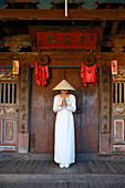 A young woman in a Non La conical hat and a traditional Ao Dai dress in the historical centre, Hoi An, Quang Nam, Vietnam, Indochina, Southeast Asia, Asia