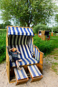 Strandkorb mit Kind und Kamera auf der Boddenseite im Lieper Winkel, Usedom, Ostseeküste, Mecklenburg-Vorpommern, Deutschland