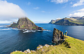 Man looks towards the sea stacks of Drangarnir and Tindholmur islet, Vagar Island, Faroe Islands, Denmark, Europe