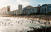 Crowded Copacabana Beach with distant view of Christ the Redeemer statue far right, Rio de Janeiro, Brazil, South America