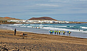 Surfer at the Playa de Famara and the village of La Caleta de Famara, Atlantic Ocean, Lanzarote, Canary Islands, Islas Canarias, Spain, Europe