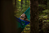 Smiling woman relaxing in hammock in forest