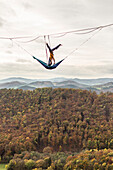 Two athletes performing acroyoga high above ground on highline, Lower Austria, Austria