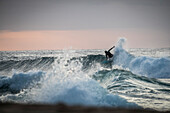 Surfer riding wave at sunset, Oahu, Hawaii, USA