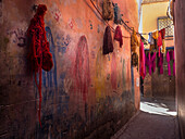 Colorful fabrics hanging in narrow alley decorated with handprints, Marrakesh, Morocco