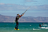 Man jumping whilst kiteboarding off the Playa de La Barca, Costa Calma, on the volcanic island of Fuerteventura, Canary Islands, Spain, Atlantic, Europe