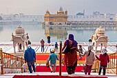 Pilgrims and sacred pool Amrit Sarovar, Golden temple, Amritsar, Punjab, India.