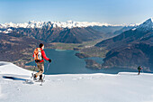 Trekker with snowshoes of Bregagno mountain, in the background Como lake. Lombardy, Italy, provence of Como