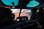 People in the cockpit of helicopter in flight towards Sassopiatto, Dolomites, South Tyrol, Italy