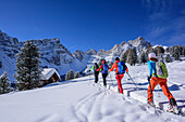 Several persons backcountry skiing ascending to Medalges, Geisler range in background, Medalges, Natural Park Puez-Geisler, UNESCO world heritage site Dolomites, Dolomites, South Tyrol, Italy