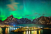 Island near Hamnoy and illuminated houses with polar lights and stary sky, northern lights, aurora borealis, Lofoten, Nordland, Norway