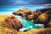 Fanad Head (Fánaid) lighthouse, County Donegal, Ulster region, Ireland, Europe. A photographer on the field at sunrise near Fanad Head lighthouse