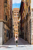 A tourist walks along the streets of Teruel. Saint Martin's tower in Background. Teruel, Aragon, Spain, Europe