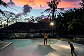 Two skateboarders riding in skate park at dusk, Jimbaran, Bali, Indonesia