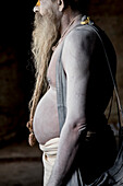 Side view of shirtless sadhu priest posing for portrait in Pashupatinath Temple, Kathmandu, Nepal