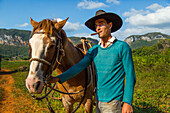 Cuban young man with a cigar and posing with his horse. Vinales, Cuba.