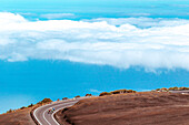 Cyclists pedaling on winding mountain road above clouds, Teide National Park, Tenerife, Canary Islands, Spain