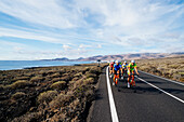 Group of road cyclists riding on road near coastline, Lanzarote, Canary Islands, Spain