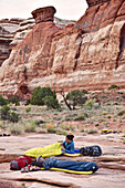 Side view of two women in sleeping bags while camping in Canyonlands National Park, Moab, Utah, USA