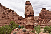 Female backpacker hiking around rock formation in The Maze section of Canyonlands National Park, Moab, Utah, USA