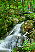 Frau beim Wandern steht auf Brücke und blickt auf Wasserfall, Höllbach-Wasserfall, Albsteig, Schwarzwald, Baden-Württemberg, Deutschland