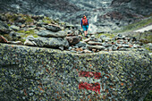 Stone chunks with signpost marker and mountaineer in the background, E5, Alpenüberquerung, 4th stage, Skihütte Zams,Pitztal,Lacheralm, Wenns, Gletscherstube, Zams to  Braunschweiger Hütte, tyrol, austria, Alps