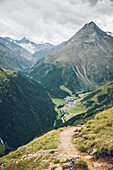 Long distance hiking path with village and summit in the background,Alpenüberquerung,5th stage, Braunschweiger Hütte,Ötztal, Rettenbachferner, Tiefenbachferner, Panoramaweg to Vent, tyrol, austria, Alps