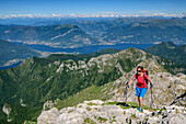 Frau beim Wandern steigt zum Grignone auf, Comer See im Hintergrund, Grignone, Grigne, Bergamasker Alpen, Lombardei, Italien
