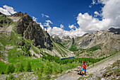 Frau beim Wandern, Bergsee und Cottische Alpen im Hintergrund, Val Maira, Cottische Alpen, Piemont, Italien