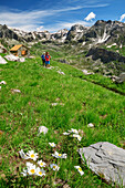 Mann und Frau beim Wandern mit Rifugio Stroppia im Hintergrund, Rifugio Stroppia, Val Maira, Cottische Alpen, Piemont, Italien
