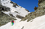 Man and woman hiking at Giro di Monviso ascending through snow towards Colle delle Traversette, Giro di Monviso, Monte Viso, Monviso, valley valle di Po, Cottian Alps, Piedmont, Italy