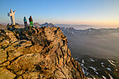 Zwei Personen beim Bergsteigen stehen auf Felsabsatz und blicken ins Tal, Viso Mozzo, Giro di Monviso, Monte Viso, Monviso, Cottische Alpen, Piemont, Italien