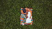 couple in love during pregnancy on a blanket in the meadows