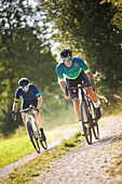 Zwei junge Männer fahren auf Gravel bikes über Feldweg, Münsing, Bayern, Deutschland