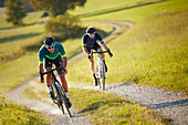 Zwei junge Männer fahren auf Gravel bikes über Feldweg, Münsing, Bayern, Deutschland