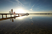 Young  woman and young man with bicycles on a jetty, Muensing, bavaria, germany