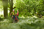 junge Frau und junger Mann Paar auf Fahrradtour in Waldstück mit Bärlauch, Kochel, Bayern, Deutschland
