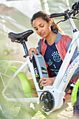 Junge Frau montiert Akku an eBike,Fahrrad, Münsing, Bayern, Deutschland