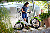 Junge Frau pumpt vor einem airstram Anhänger Reifen auf, eBike,Fahrrad, Münsing, Bayern, Deutschland