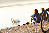 junge Frau  und junger Mann Paar sitzen mit Fahrrädern am Seeufer, Starnberger See, Bayern, Deutschland