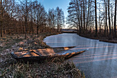 Im Eis eingefrorener Kahn in einem Fluss des Spreewaldes zur blauen Stunde im Morgengrauen