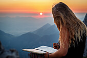 Junge Frau am Gipfel, Eintrag ins Gipfelbuch bei Sonnenaufgang, Scheffauer, Wilder Kaiser, Tirol, Österreich