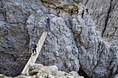 Several persons at fixed-rope route Pisciadu walking on suspension bridge over gorge, fixed-rope route Pisciadu, Sella range, Dolomites, UNESCO World Heritage Site Dolomites, South Tyrol, Italy